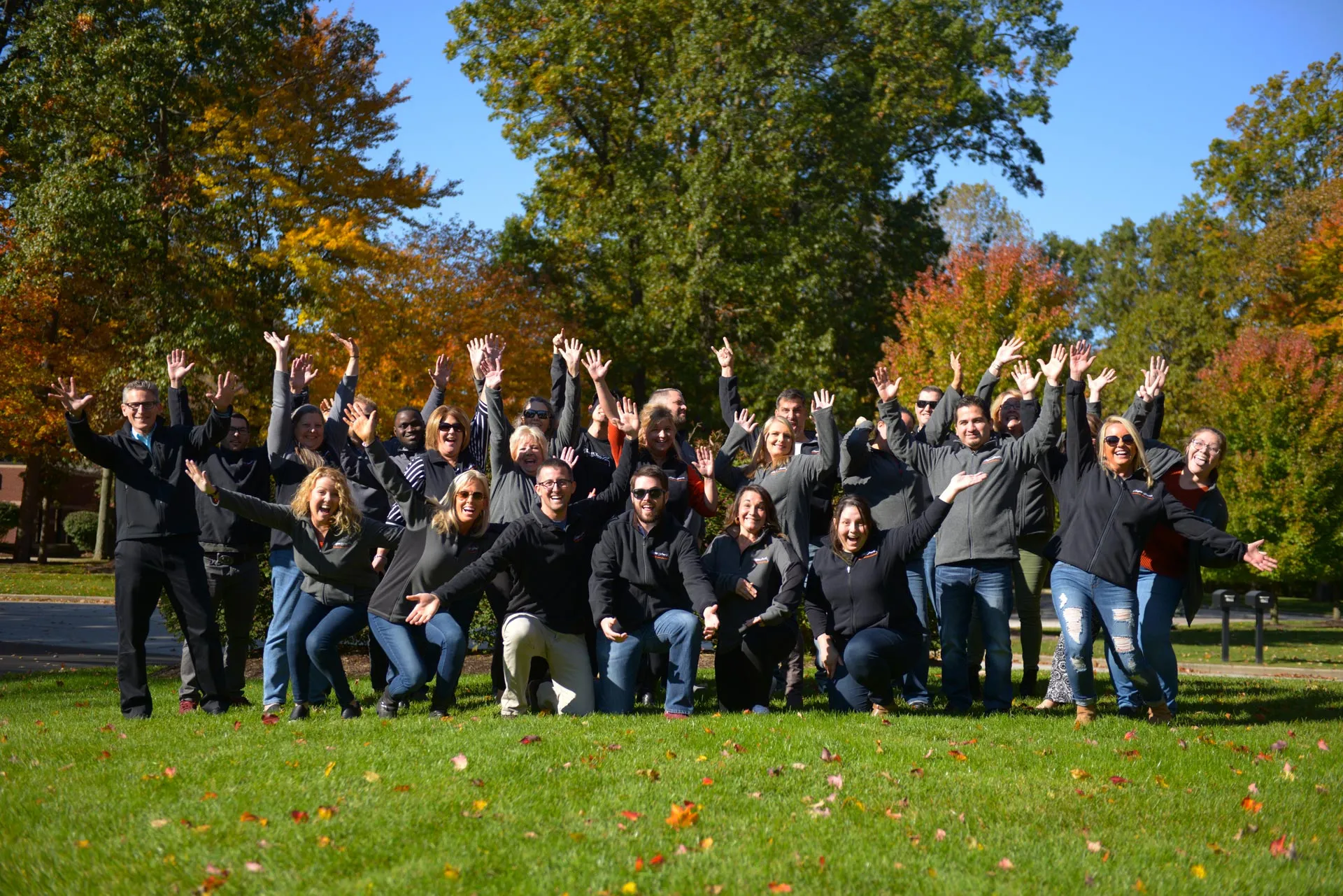 Cooper Smith team photo - a group of professionals in dark clothing outdoors raising their hands in celebration